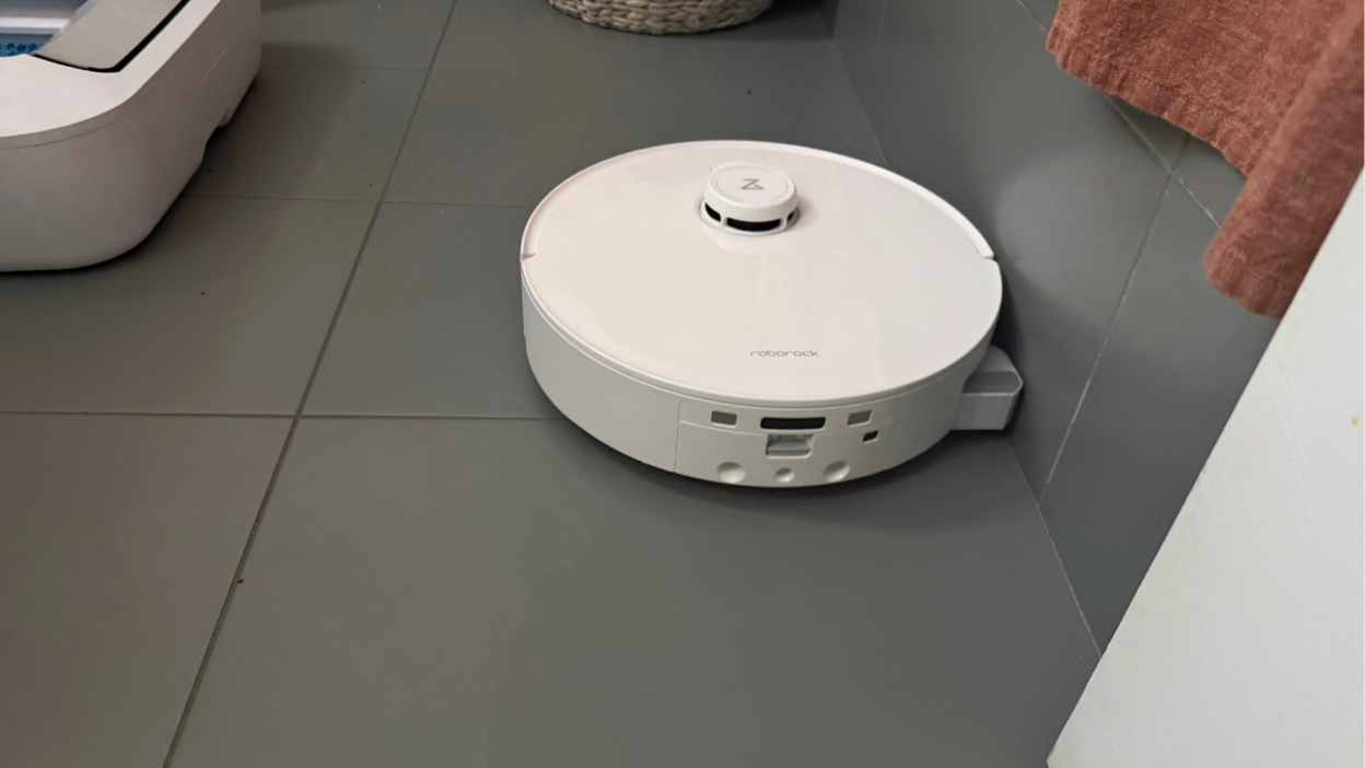 Roborock Qrevo Curv 2 Flow robot vacuum mopping gray tile bathroom floor near shower