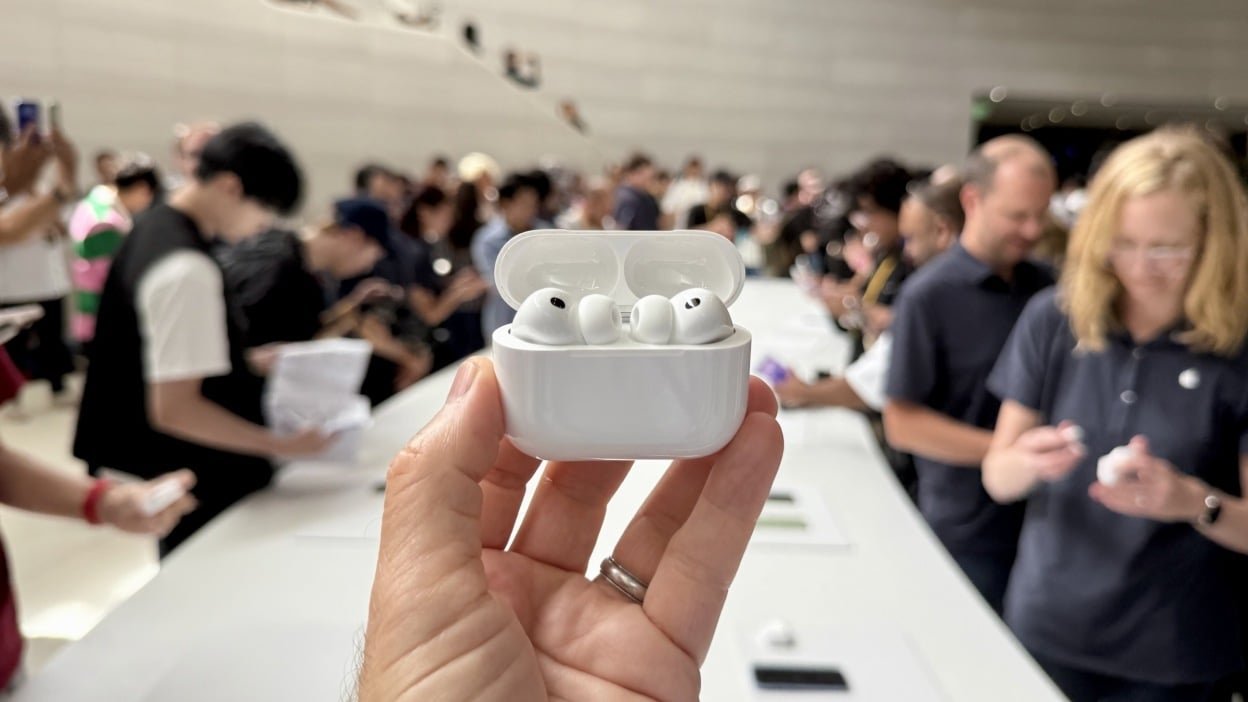 woman holding up apple airpods pro 3 at apple park headquarters